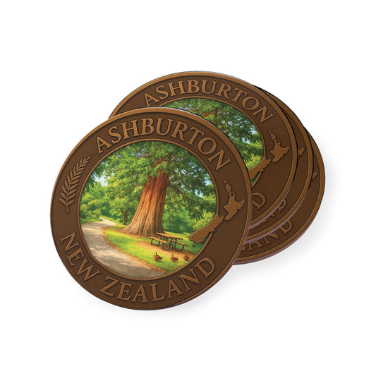 Two round wooden coasters with Ashburton, New Zealand design featuring a tree and path.