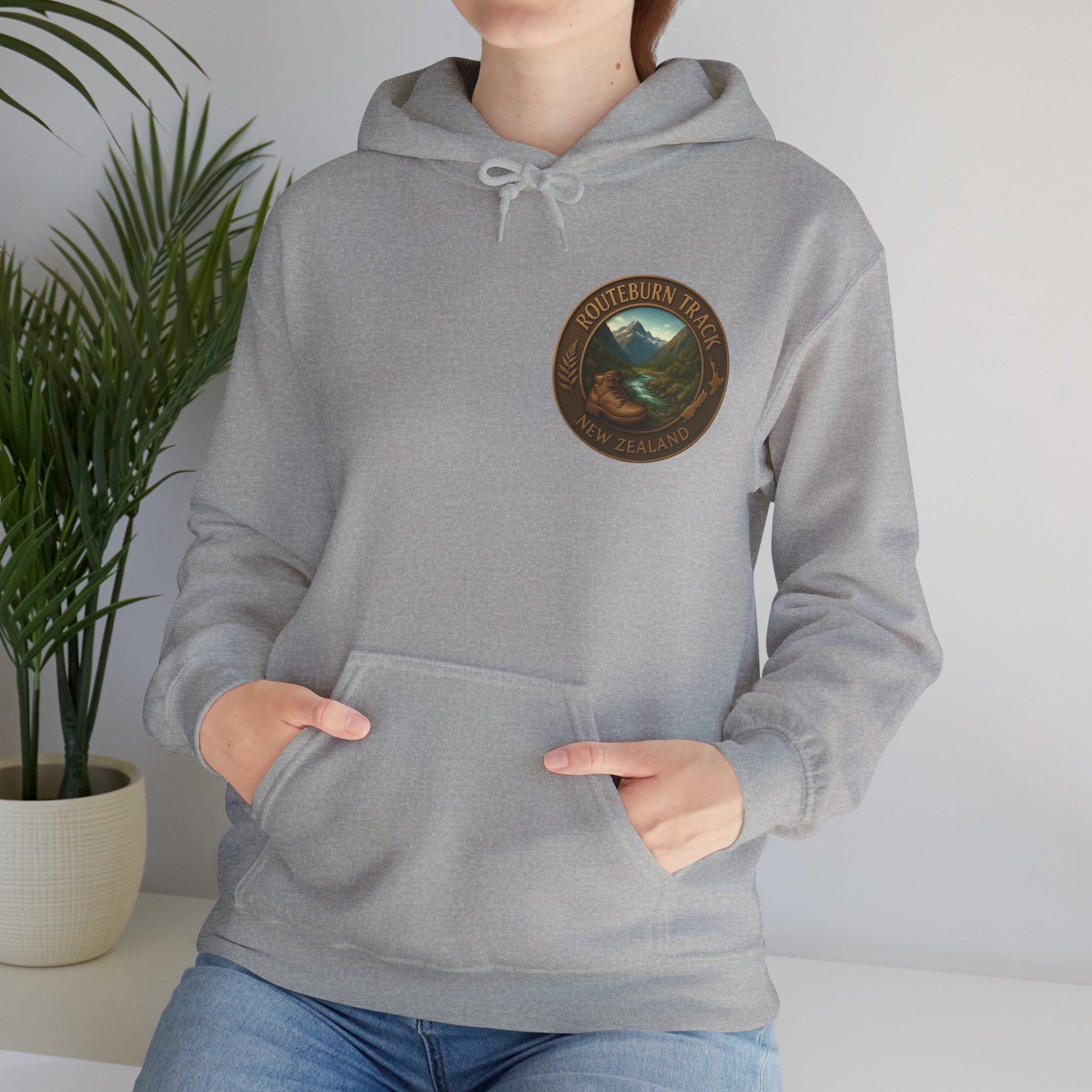 Person wearing a gray Routeburn Track hoodie with a logo on a plain background