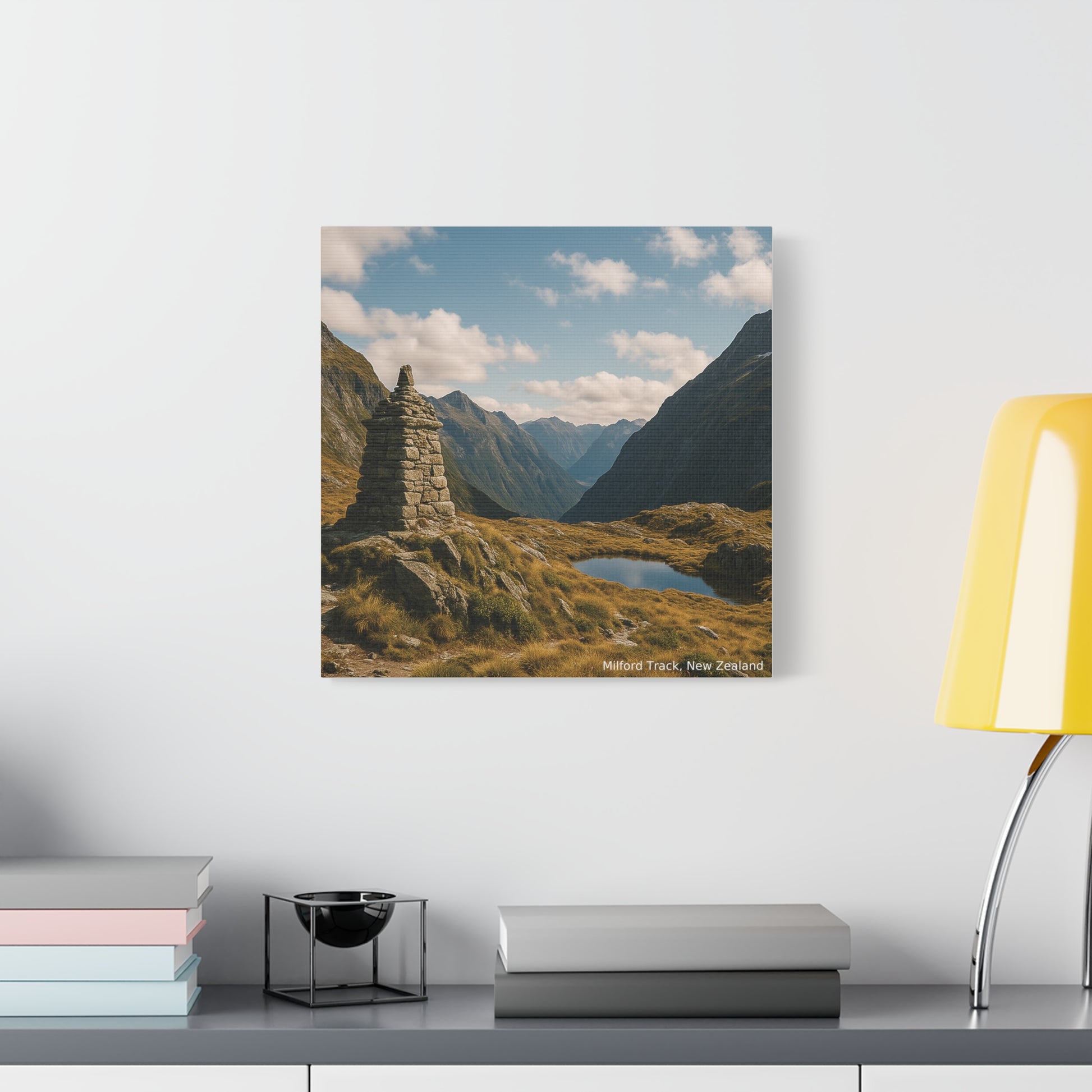 Canvas print of a mountain landscape on a wall above a shelf with books and decor.