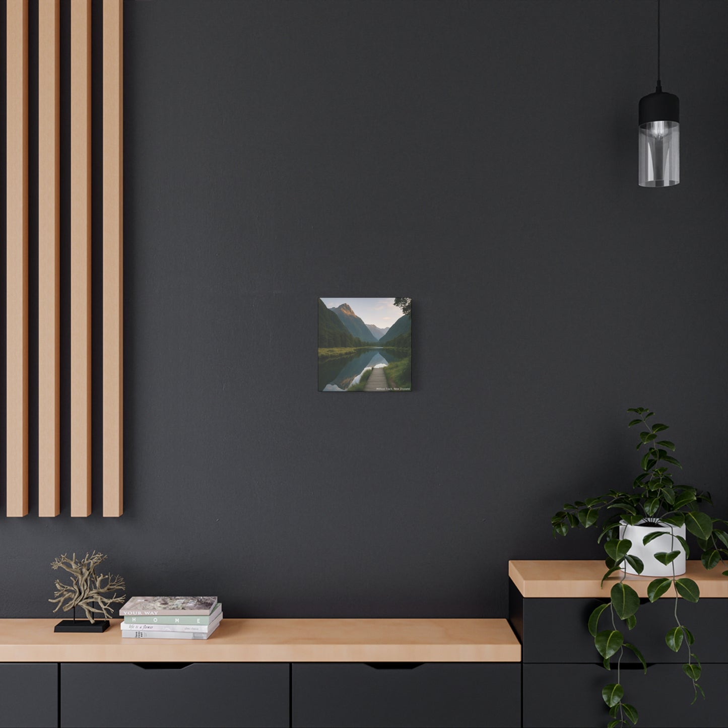 Modern interior with a dark wall, wooden shelf, and framed Milford Track landscape print.