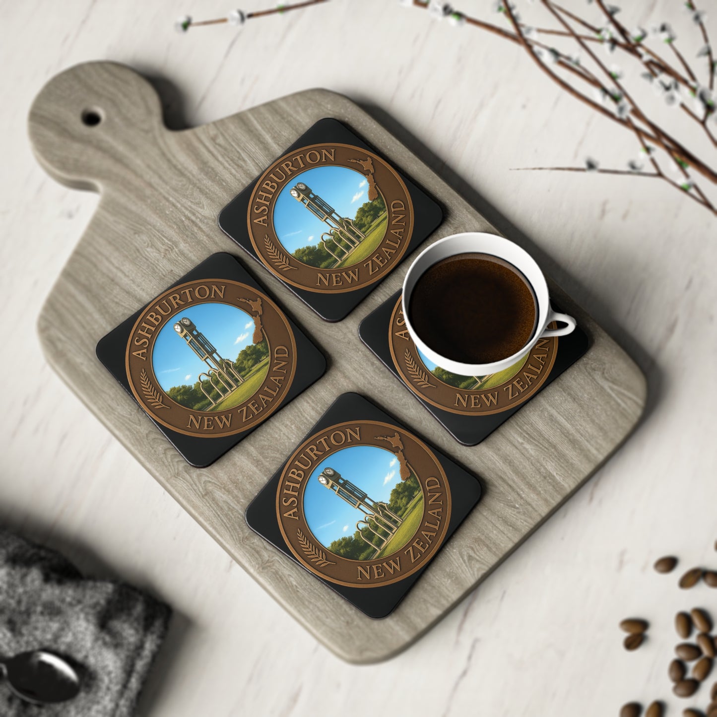 Set of four coasters with Ashburton, New Zealand design on a wooden board with a cup of coffee.