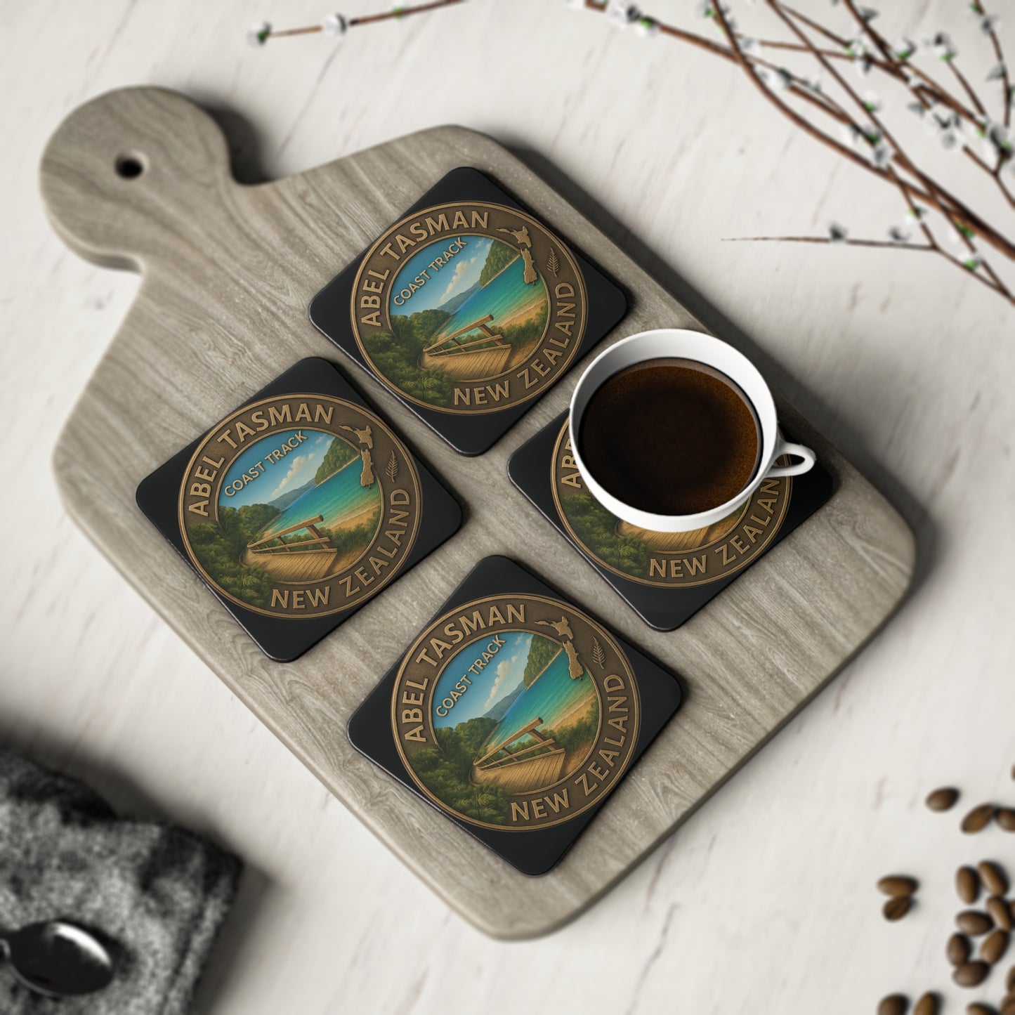 Set of four Abel Tasman New Zealand coasters with a cup of coffee on a wooden board.
