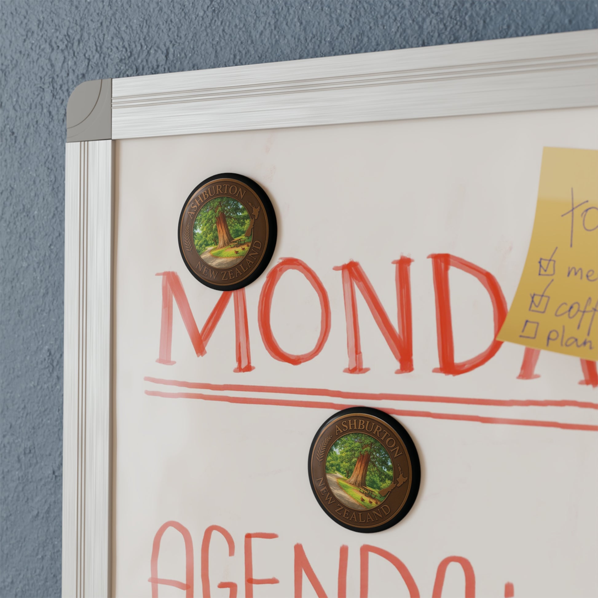 Whiteboard with 'Monday Agenda' and decorative magnets on a gray wall
