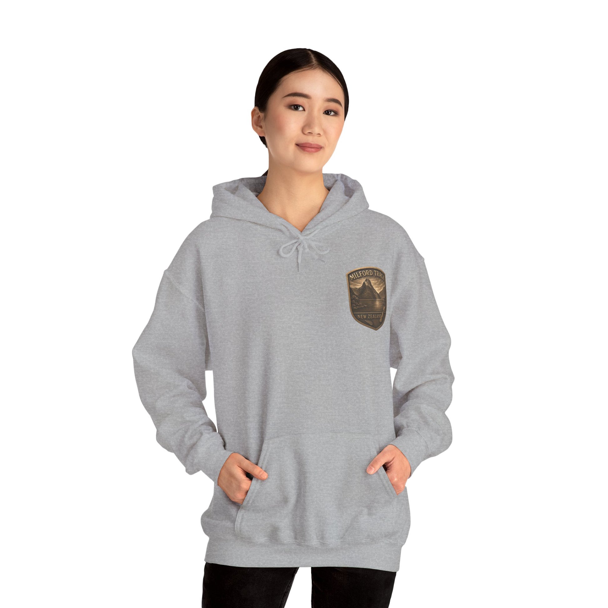 Person wearing a gray Milford Track hoodie with a patch on a white background