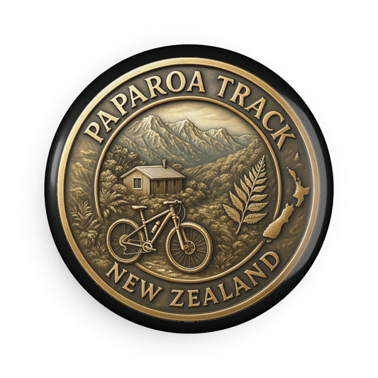 Bronze-colored Fridge Magnet with 'Paparoa Track, New Zealand' text, mountain, cabin, and bike illustration.