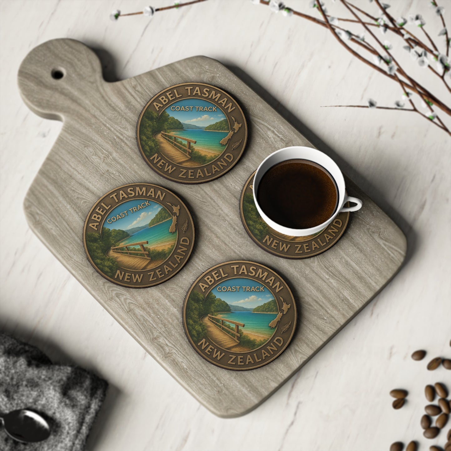 Abel Tasman Coasters with New Zealand design on a wooden board with a cup of coffee.