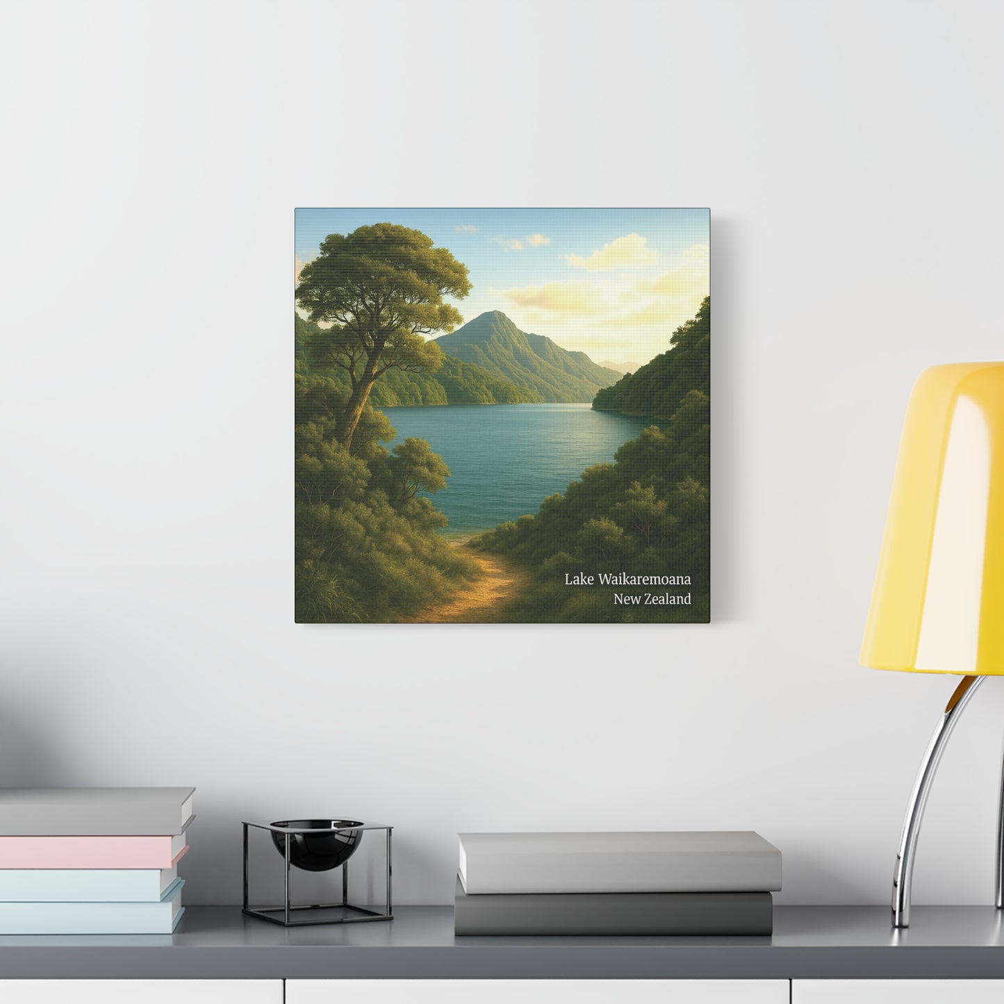Framed landscape print of Lake Waikaremoana Track in New Zealand on a wall above a shelf.