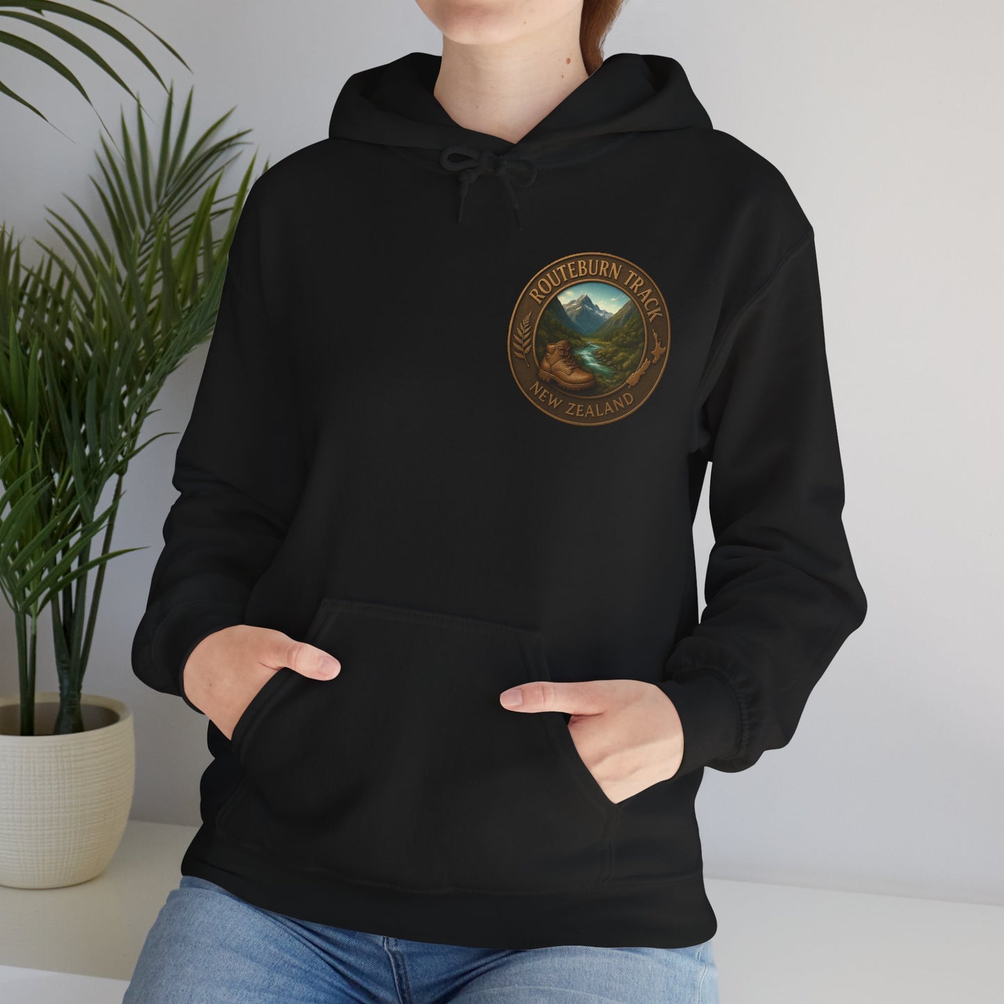 Person wearing a black Routeburn Track hoodie with a logo on a plain background