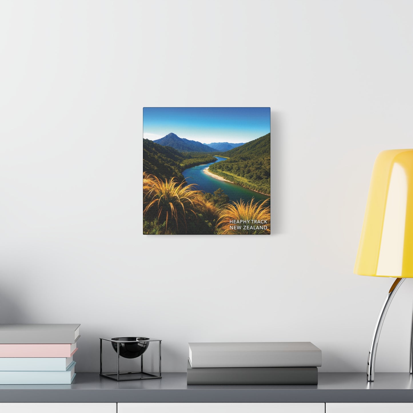Heaphy Track Framed print of a mountain landscape with a river on a wall above a desk.