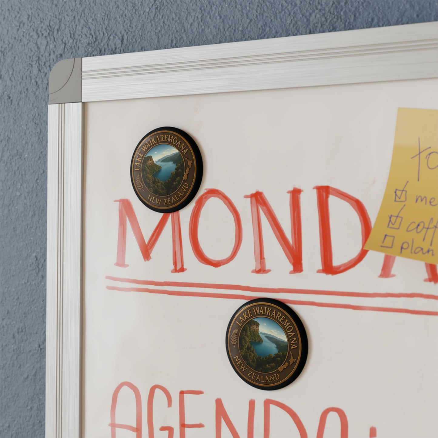 Whiteboard with 'MONDAY' and 'AGENDA' text, featuring Lake Waikaremoana Track logo, on a blue wall.