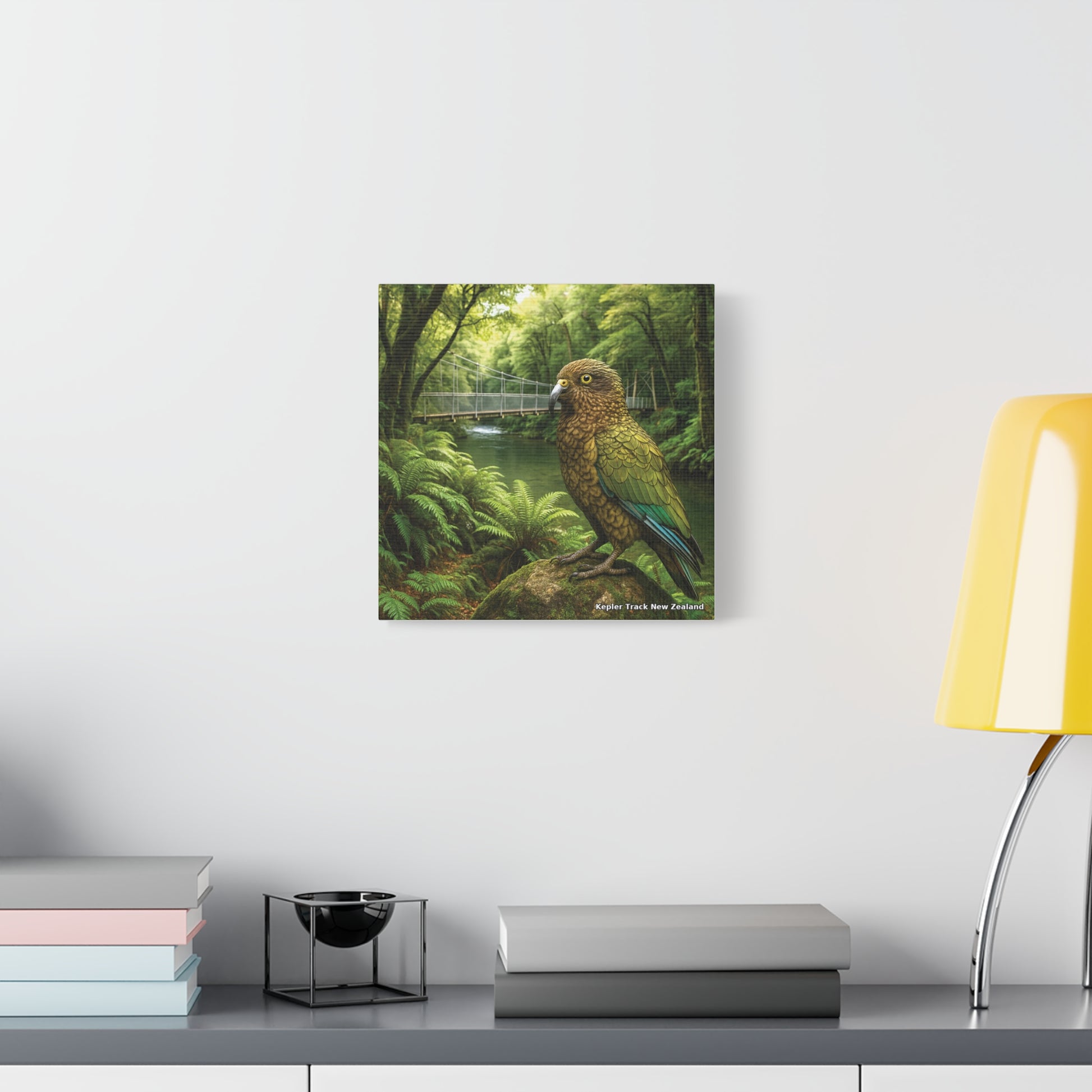 Framed artwork of a parrot in a forest setting on a wall above a desk with books and a lamp.