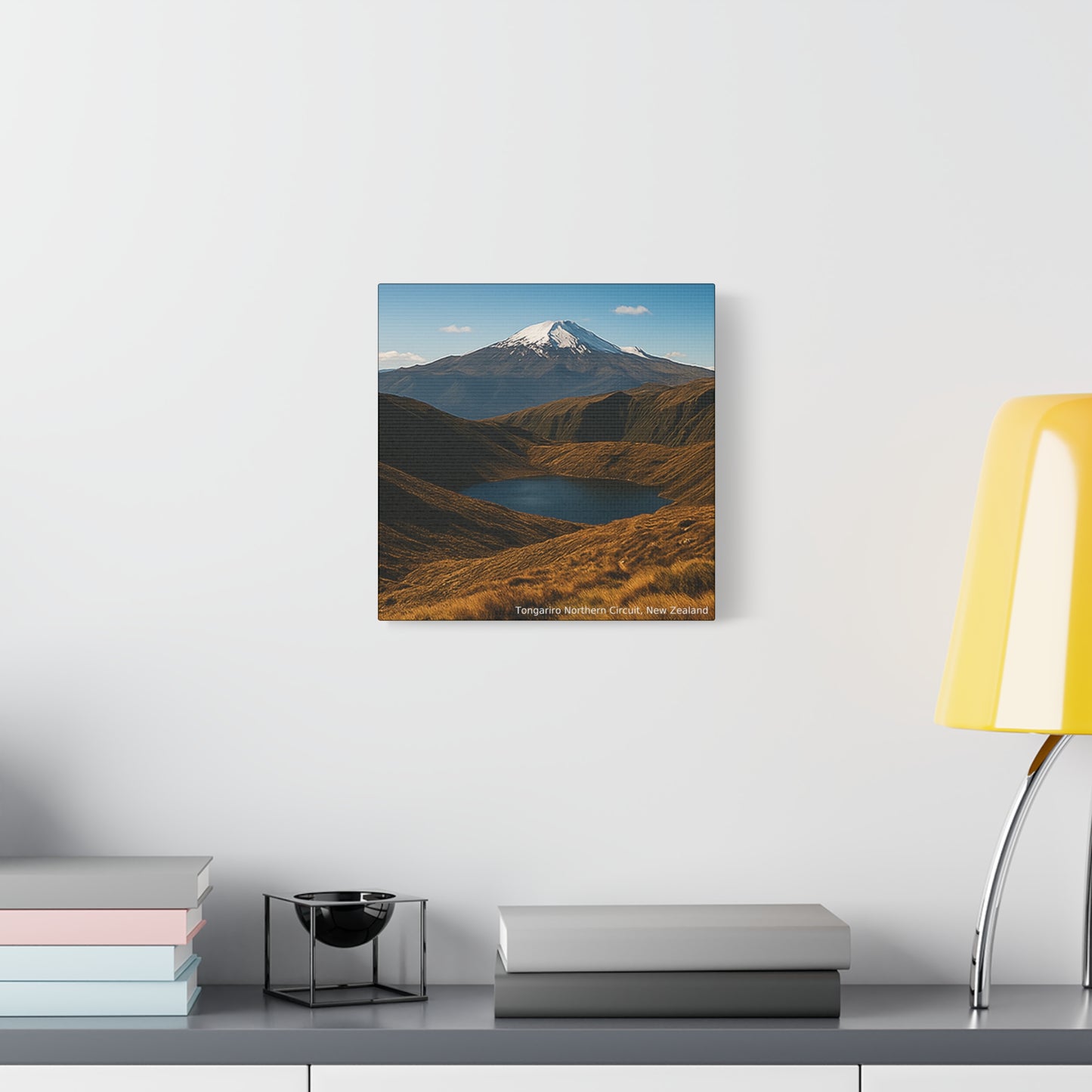 Tongariro Northern Circuit Framed mountain landscape print on a wall above a desk with books and a lamp.