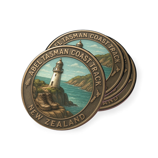 Bronze coin with lighthouse design and 'Abel Tasman Coast Track, New Zealand' text on a white background