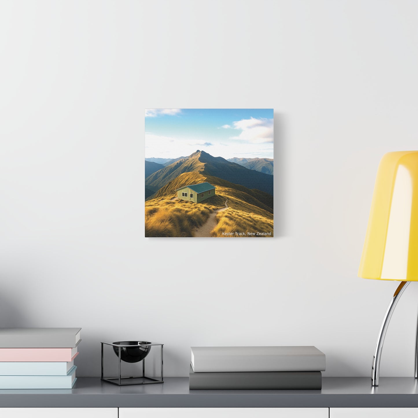 Kepler Track Canvas print of a mountain landscape with a cabin on a white wall above a desk.