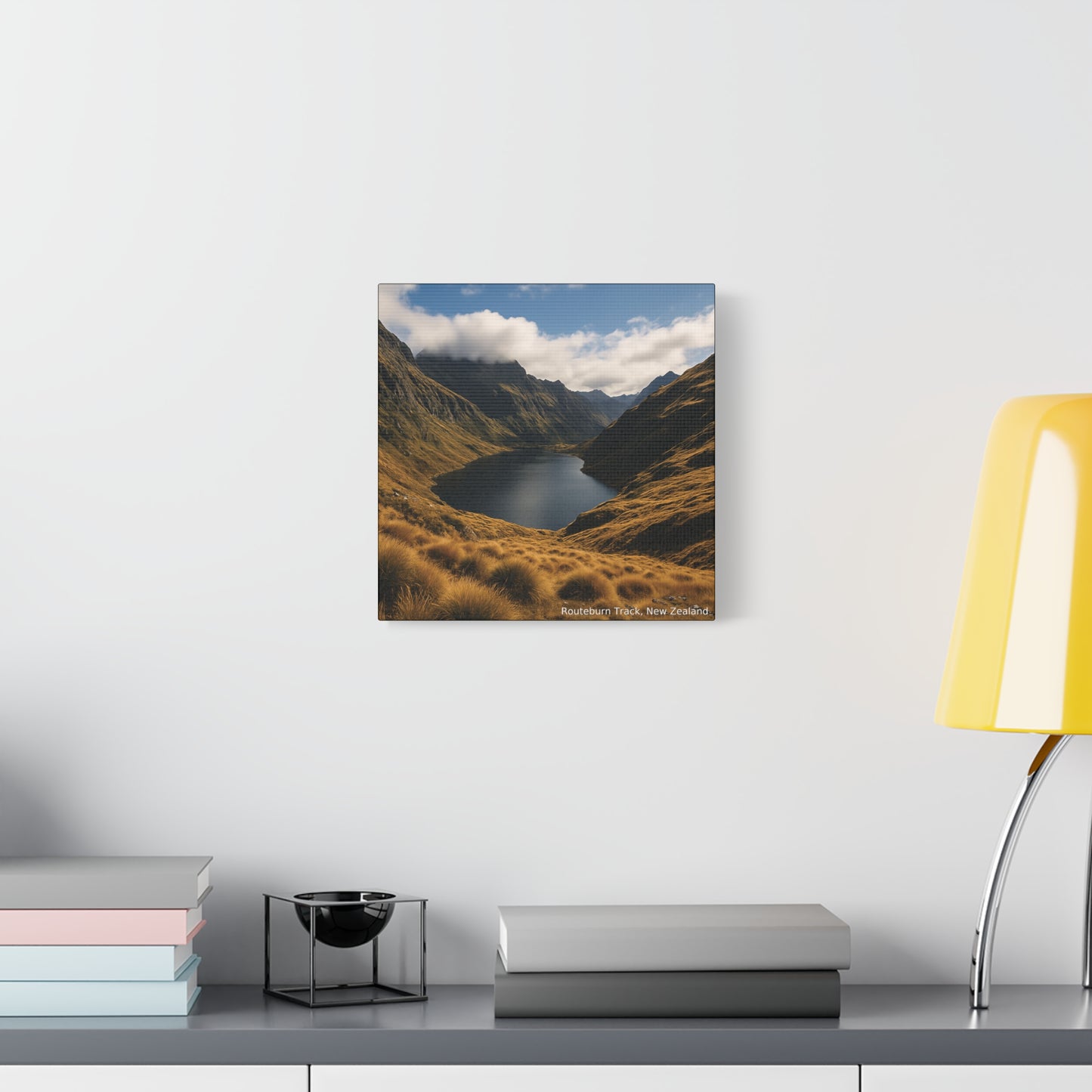 Routeburn Track Framed mountain landscape print on a wall above a desk with books and a lamp.